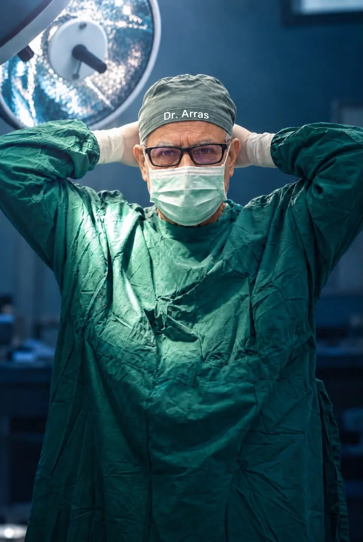 El Dr. Heriberto Arras con bata quirúrgica verde en el quirófano